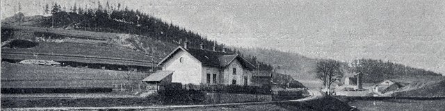 Pohled přes nádraží na dávno odtěžený kopec Smrk s lomy na úbočí. Za nádražím je patrná šikmá úzkokolejná dráha pro dopravu materiálu k nedaleké Musilově vápence. (~1906)